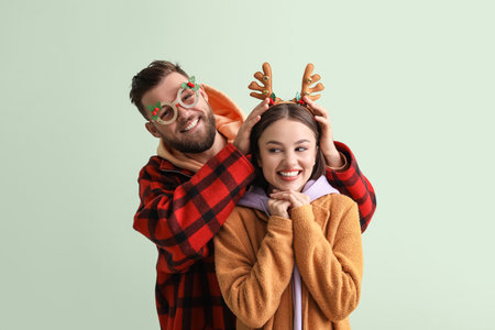 Happy young couple in stylish winter clothes and with Christmas decor on light backgroundの写真素材