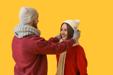 Young couple in stylish winter clothes on color backgroundの写真素材
