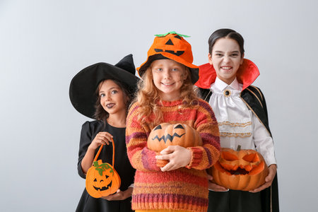 Cute little children in Halloween costumes on light backgroundの写真素材