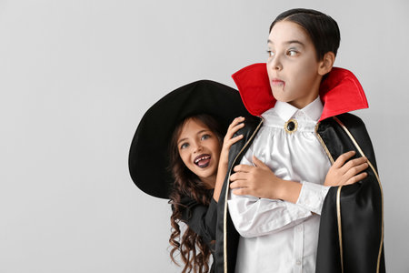 Cute little children in Halloween costumes on light backgroundの写真素材