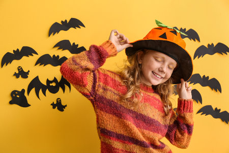 Cute little girl dressed for Halloween on color backgroundの写真素材