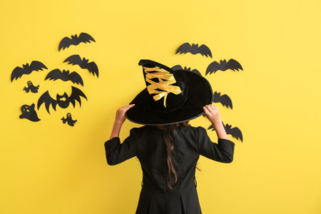 Cute little girl dressed as witch for Halloween on color backgroundの写真素材