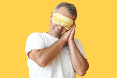 Mature man with sleep mask on color backgroundの写真素材