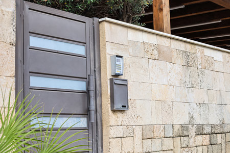 View of fence with metal door, intercom and mailbox