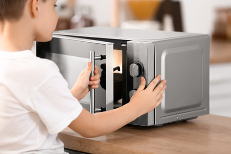 Little boy heating food in microwave ovenの写真素材