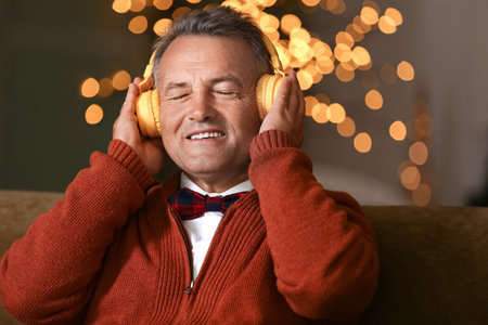Mature man listening to Christmas music at homeの写真素材