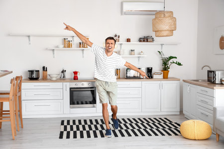 Dancing young man with headphones in the kitchenの写真素材