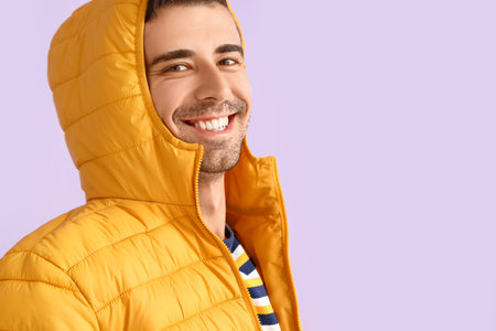 Young man in yellow jacket on lilac backgroundの写真素材