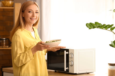 Mature woman heating food in microwave ovenの写真素材