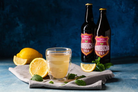 Bottles and glass of fresh kombucha with lemon and mint on color backgroundの写真素材