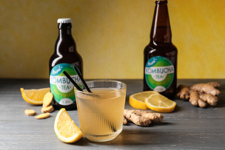 Bottles and glass of tasty kombucha with lemon and ginger on tableの写真素材