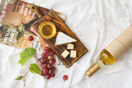 Ripe grapes, cheese and glass of wine on light backgroundの写真素材