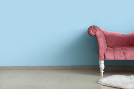 Elegant pink armchair and fluffy carpet near blue wall