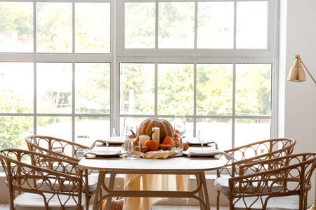 Dining table with pumpkins near window in roomの写真素材