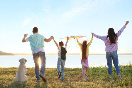 Happy family with kite and cute dog near riverの写真素材