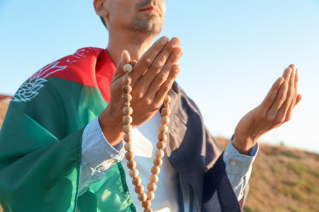 Praying Muslim man with flag of Afghanistan and tasbih outdoorsの写真素材