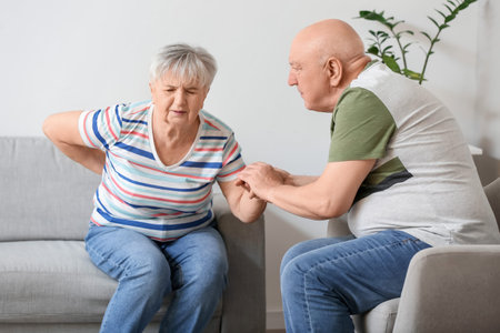 Senior man with his wife suffering from back pain at home