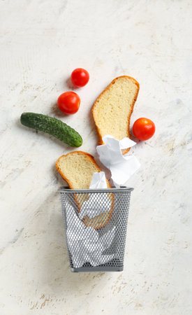 Trash can with food on light background. anorexia concept
