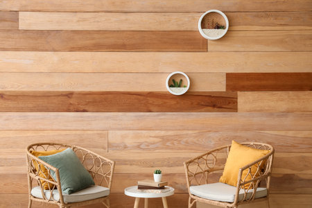 Wicker chairs and coffee table near wooden wall