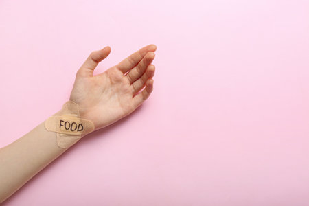 Female hand with plasters and word FOOD on color background. anorexia conceptの写真素材