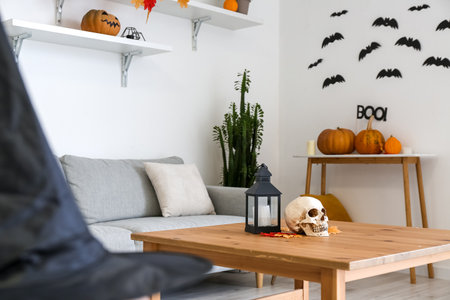 Human skull with candle and fallen leaves on table in roomの写真素材