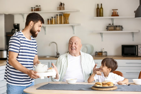 Happy man, his little son and father having breakfast in the kitchen