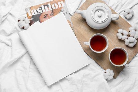 Composition with blank magazine and tea on bedの写真素材