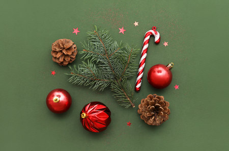 Composition with fir branch, Christmas decorations and pine cones on green background