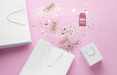 Shopping bags with tags and confetti on pink background. black friday saleの写真素材
