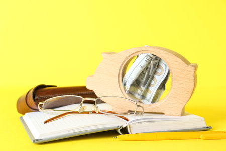 Piggy bank with notebook and eyeglasses on yellow background. budget conceptの写真素材
