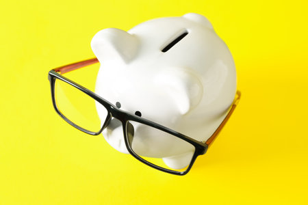 Piggy bank with eyeglasses on yellow background. budget conceptの写真素材