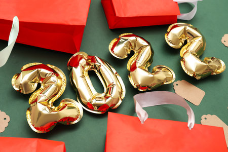 Number 2022 made of balloons, shopping bags and tags on green background. black friday sale