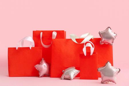 Red shopping bags and balloons on pink background. black friday saleの写真素材