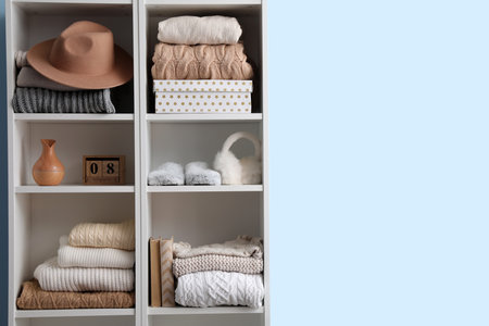 Shelving unit with sweaters, hat and decor near blue wallの写真素材