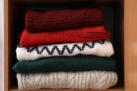 Shelving unit with folded sweaters in room, closeup