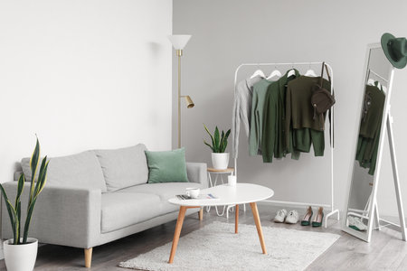 Interior of light living room with rack, sweaters and sofaの写真素材