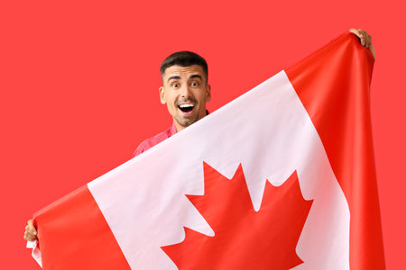 Happy young man with Canadian flag on red backgroundの写真素材