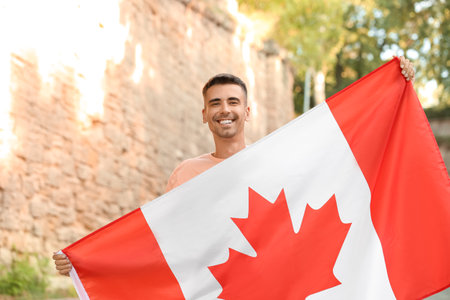 Young man with flag of Canada outdoorsの写真素材