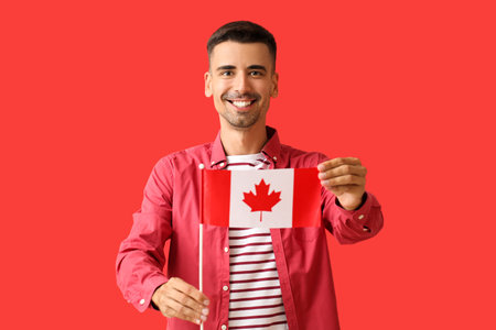Happy young man with Canadian flag on red backgroundの写真素材