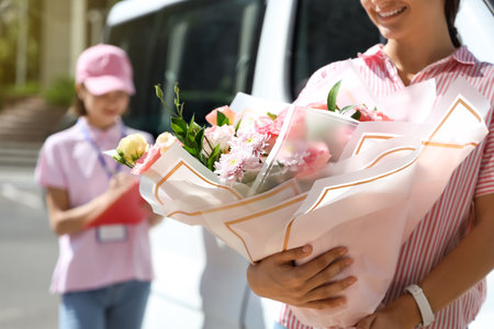 Woman with bouquet of flowers received from courier outdoorsの写真素材