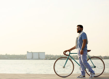 Young bearded man with bicycle near the riverの写真素材