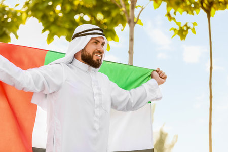 Smiling Muslim man with UAE flag outdoorsの写真素材