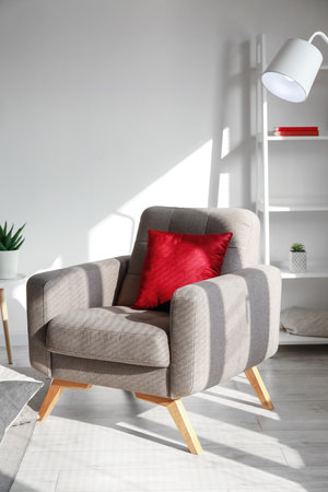Soft armchair with red cushion in light living roomの写真素材