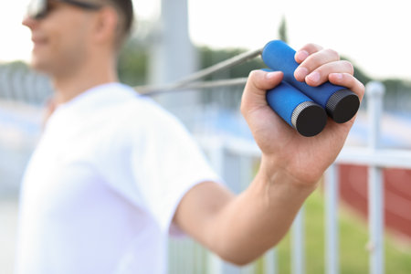 Sporty young man with skipping rope near stadium, closeupの写真素材