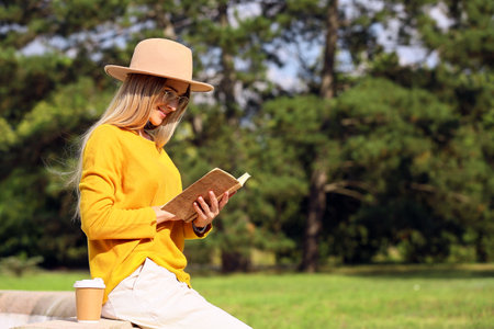 beautiful woman reading book in parkの写真素材