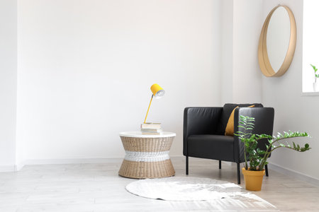 Black armchair, table and houseplant in interior of light living roomの写真素材