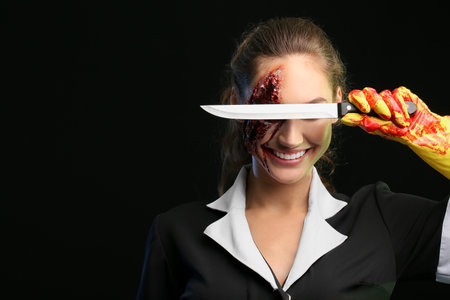 Woman dressed for Halloween as chambermaid with knife on dark backgroundの写真素材