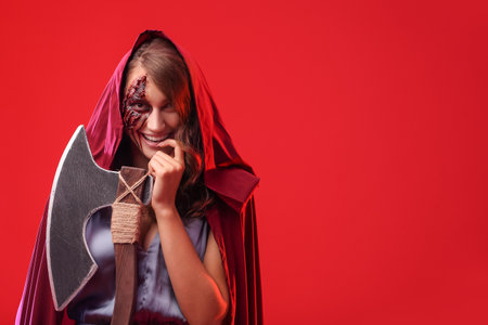 Young woman with Halloween makeup and ax on color background