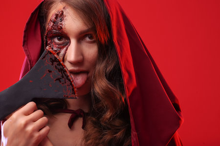 Crazy woman with Halloween makeup and ax on color backgroundの写真素材
