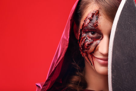 Young woman with Halloween makeup and ax on color backgroundの写真素材
